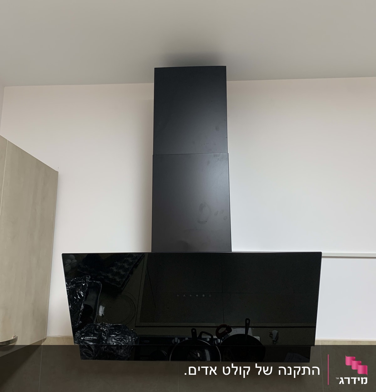 קולט אדים שחור מותקן על קיר מטבח